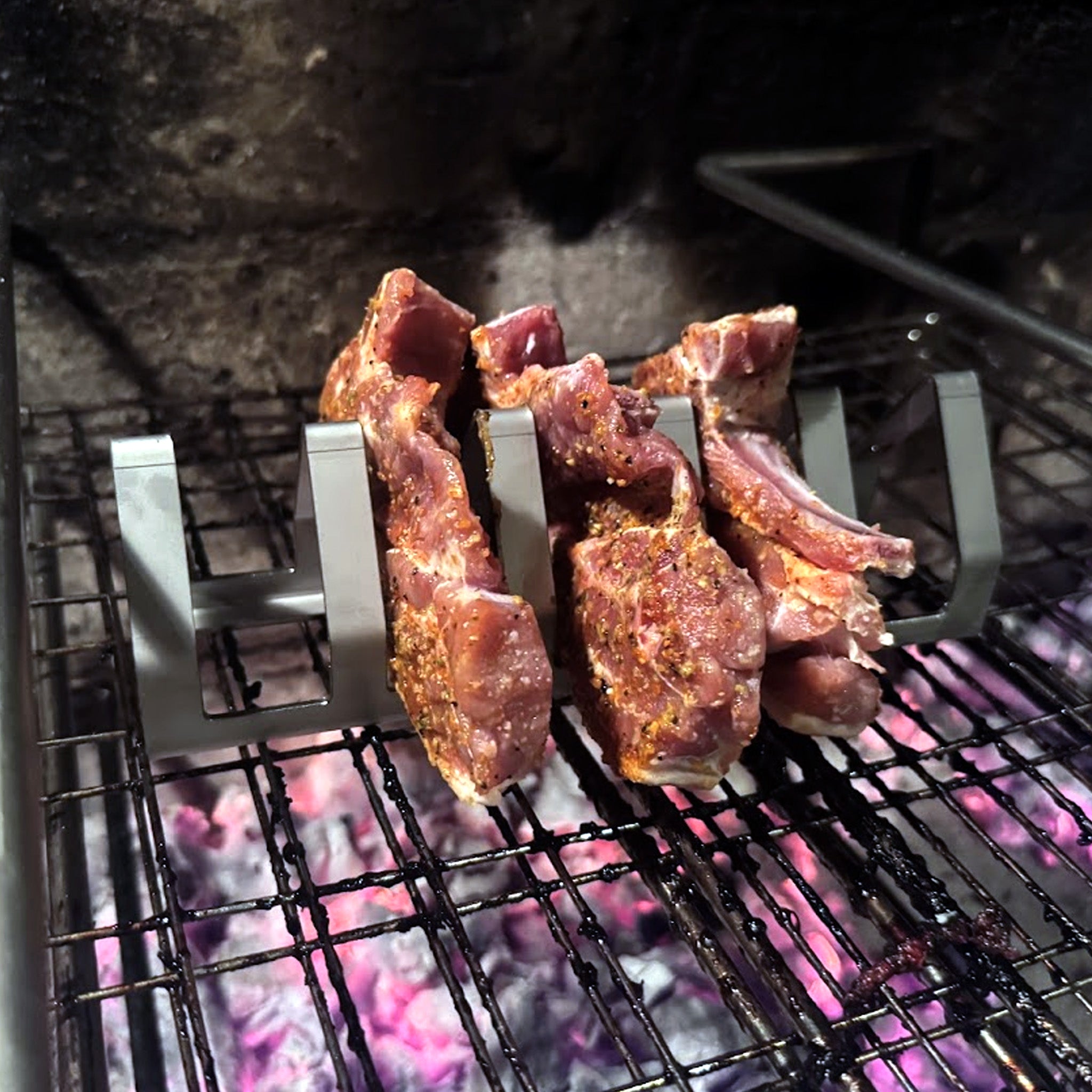 Stainless steel tjop stand holding seasoned lamb tjops grilling over open flame charcoal