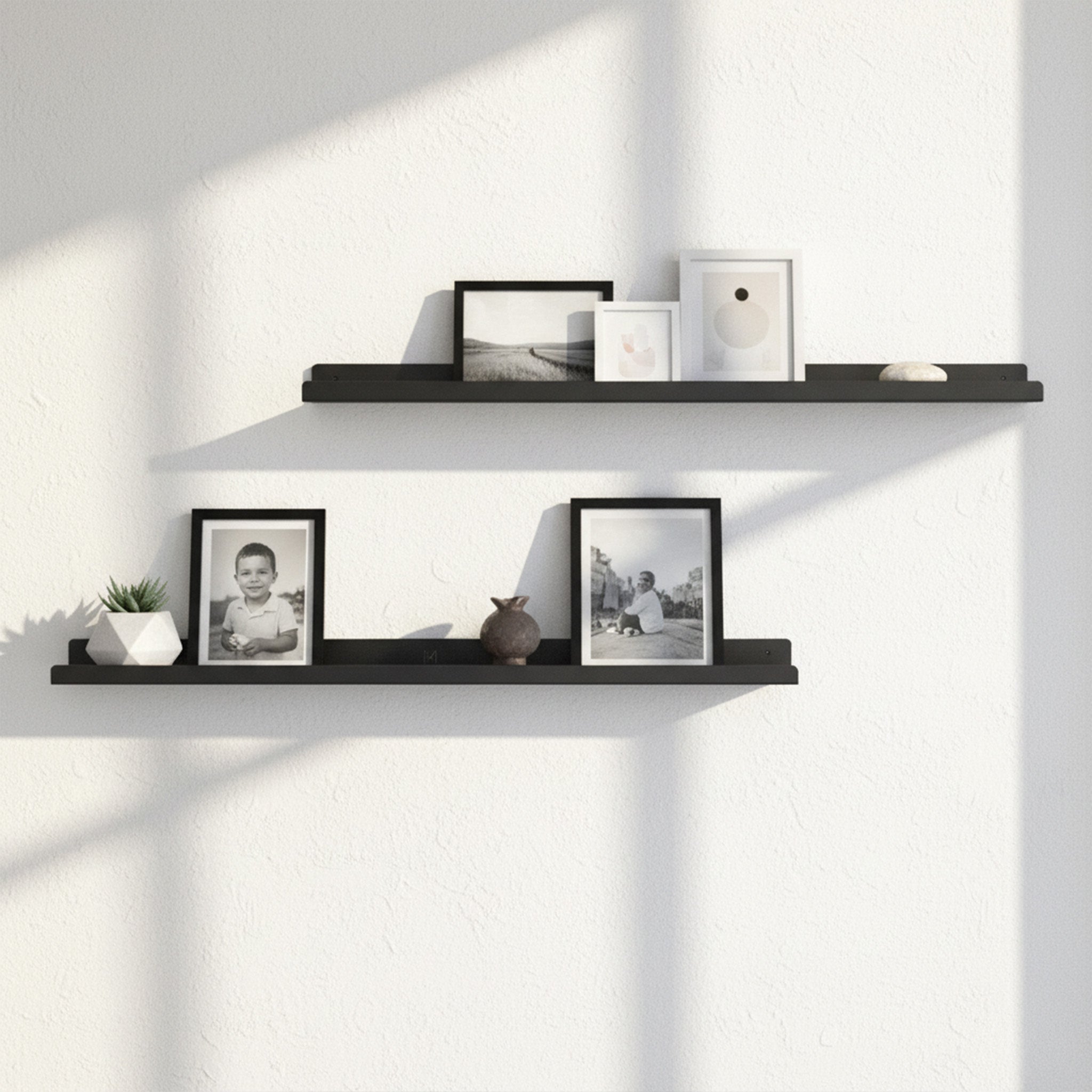 600mm wide black powder-coated steel lip shelf holding photo frames and decor on white wall